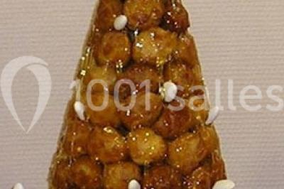 Pyramide de macarons colorés surmontée de figurines de mariés, présentée sur une table rouge en extérieur.