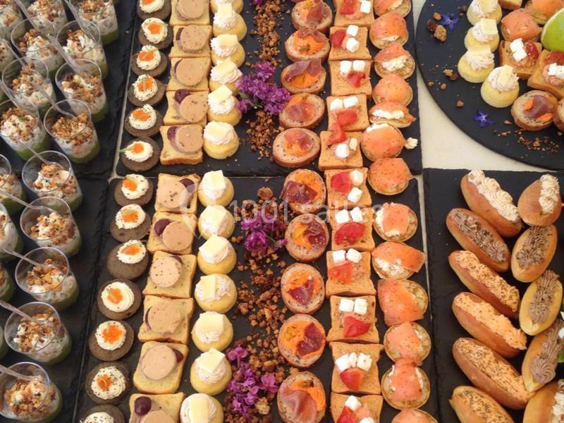 Plateau de bouchées variées comprenant verrines, toasts garnis, mini-sandwichs et décorations florales.