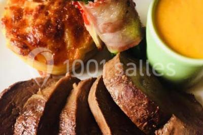 Assiette de saumon fumé tranché avec noix, graines et herbes, accompagnée de pain, fromage et citron sur une table.