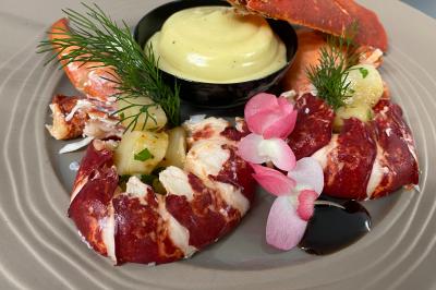 Assiette de saumon fumé tranché avec noix, graines et herbes, accompagnée de pain, fromage et citron sur une table.