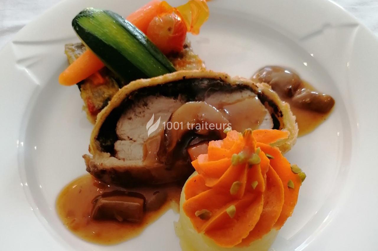Plat composé d'un filet de viande en croûte, purée décorée, légumes et sauce servie dans une assiette blanche.