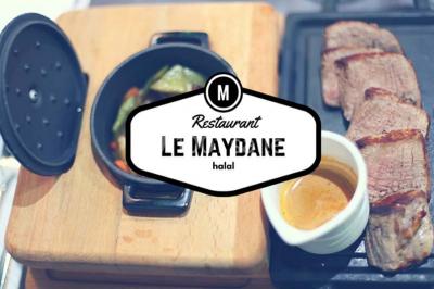 Plat de viande grillée avec sauce et légumes dans une cocotte, présenté sur une planche en bois.