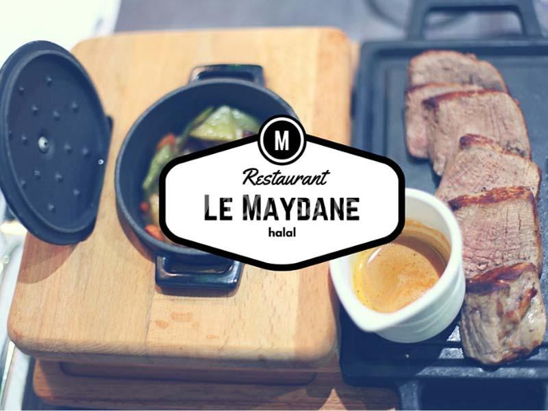 Plat de viande grillée avec sauce et légumes dans une cocotte, présenté sur une planche en bois.