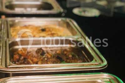 Plat de viande grillée avec sauce et légumes dans une cocotte, présenté sur une planche en bois.