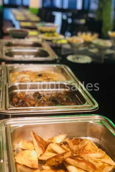 Buffet avec des plats variés, incluant des samoussas et des préparations chaudes dans des bacs en inox.