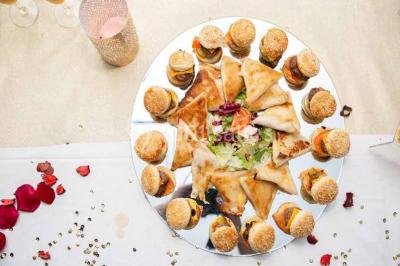 Plat de viande grillée avec sauce et légumes dans une cocotte, présenté sur une planche en bois.