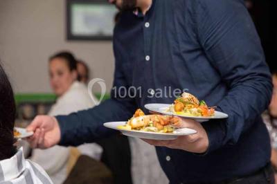 Plat de viande grillée avec sauce et légumes dans une cocotte, présenté sur une planche en bois.