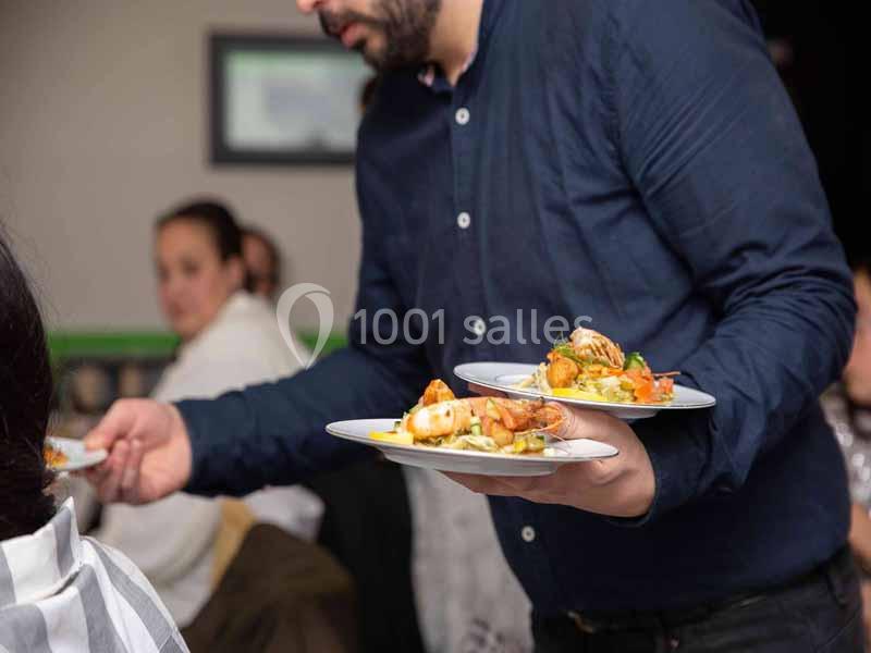 Un serveur portant deux assiettes garnies de plats variés dans un restaurant.