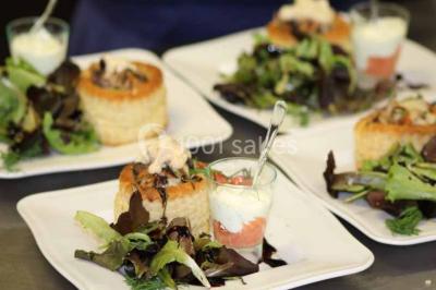Plat de viande grillée avec sauce et légumes dans une cocotte, présenté sur une planche en bois.