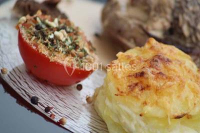 Plat de viande grillée avec sauce et légumes dans une cocotte, présenté sur une planche en bois.