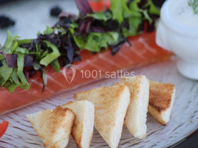 Tranches de saumon fumé accompagnées de pain grillé, salade verte et sauce blanche dans un bol.