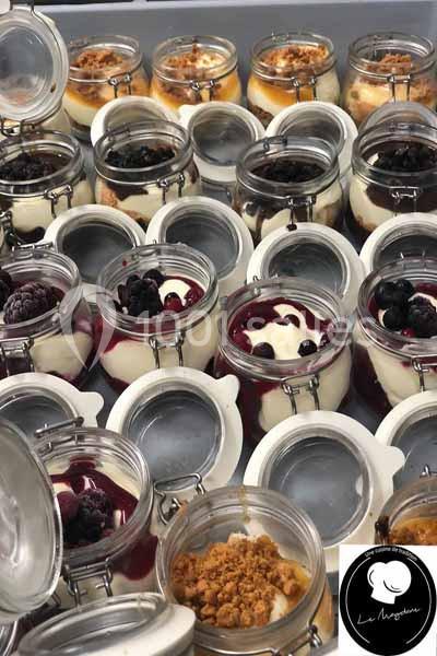 Desserts en verrines avec divers toppings comme fruits rouges, crumble et coulis, présentés dans des pots en verre.