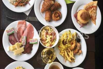 Plat de viande grillée avec sauce et légumes dans une cocotte, présenté sur une planche en bois.