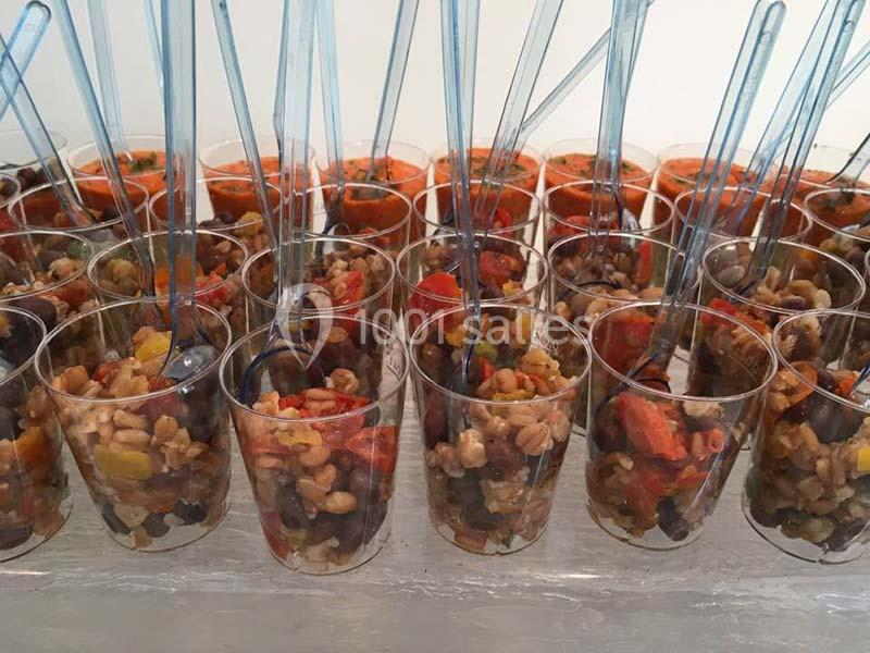 Verrines remplies de salade de céréales, légumes colorés et cuillères transparentes, alignées sur une table.