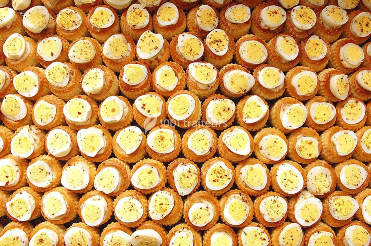 Assortiment de bouchées garnies d'œufs durs tranchés et saupoudrées d'épices, disposées en rangées serrées.