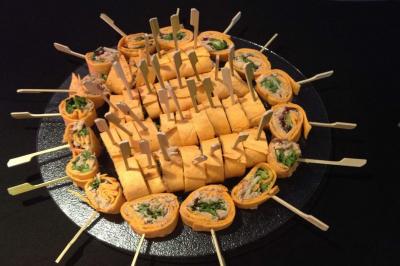 Plateau de bouchées variées comprenant mini-sandwichs, macarons, brochettes, verrines et roulés aux légumes.