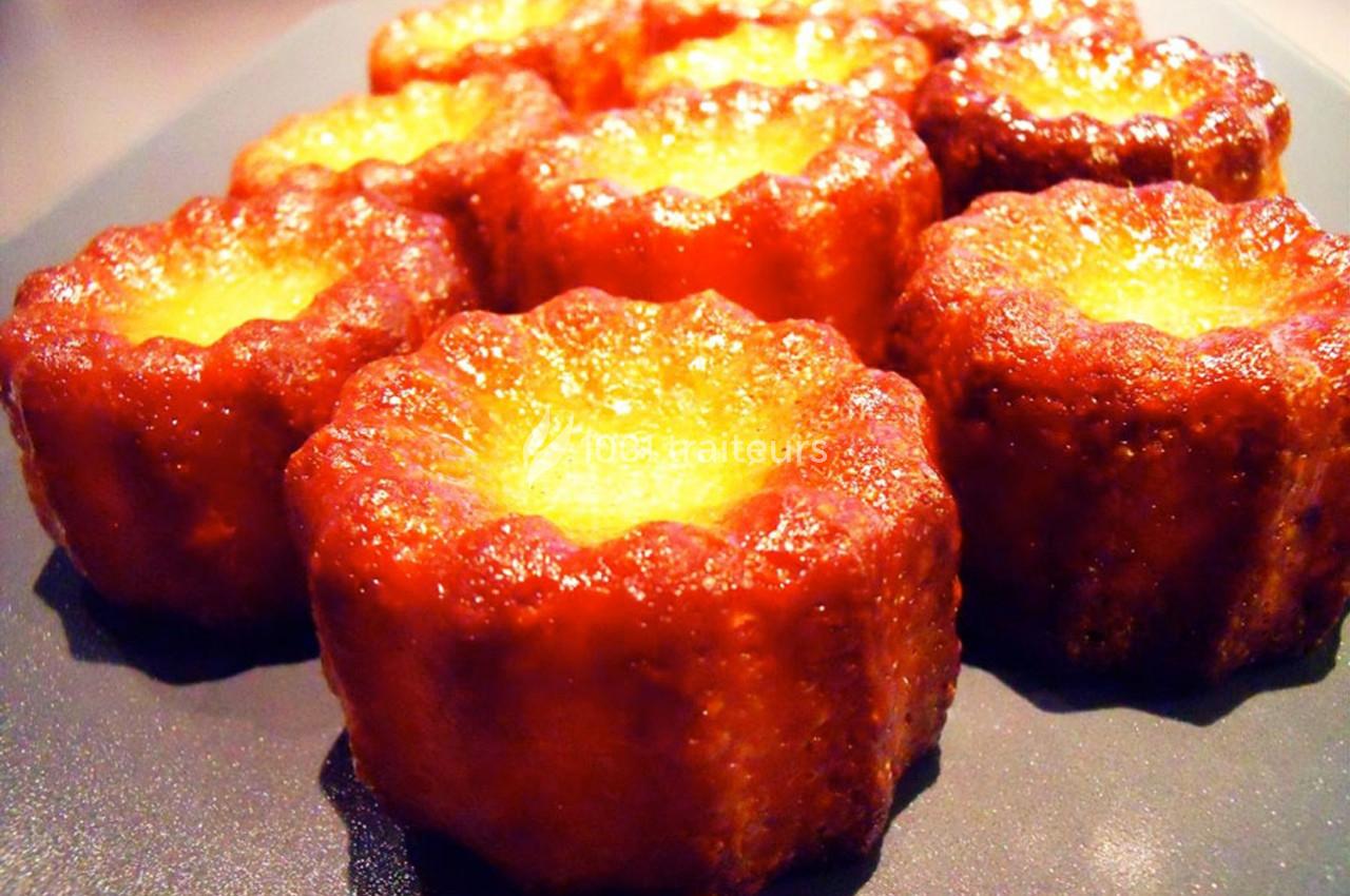 Cannelés dorés et caramélisés disposés sur une surface sombre.