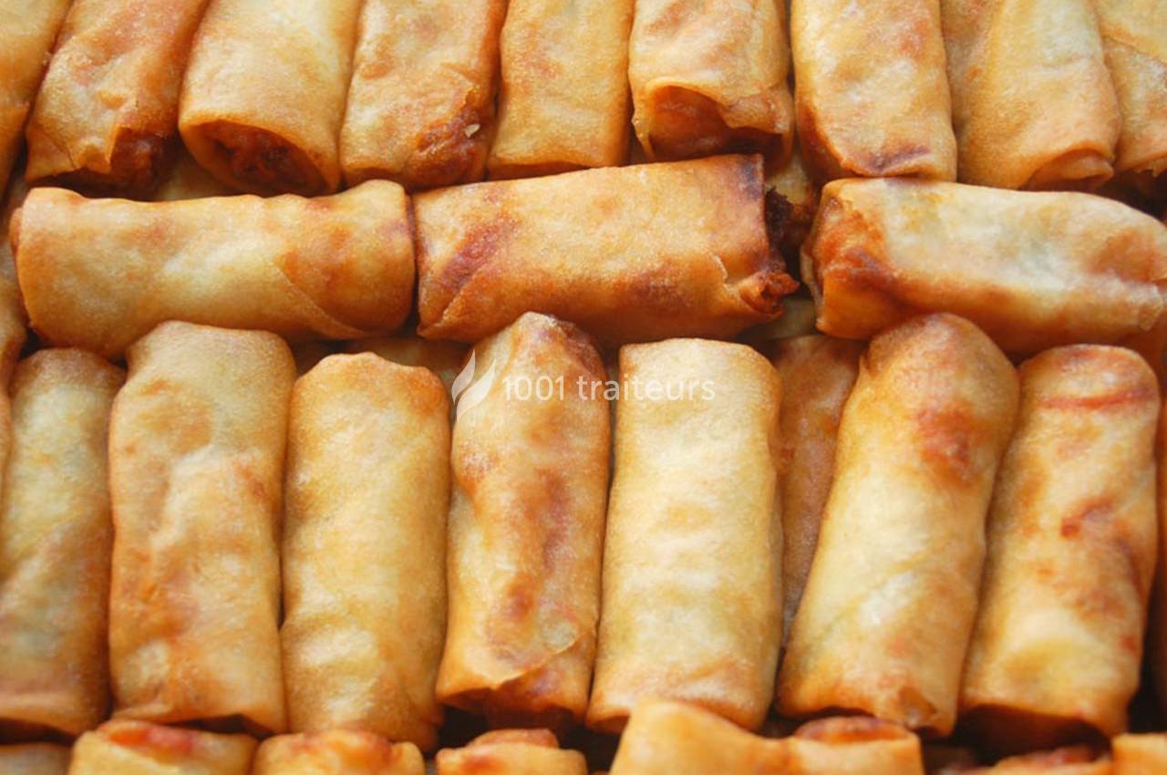 Rouleaux de printemps frits dorés alignés en rangées serrées.