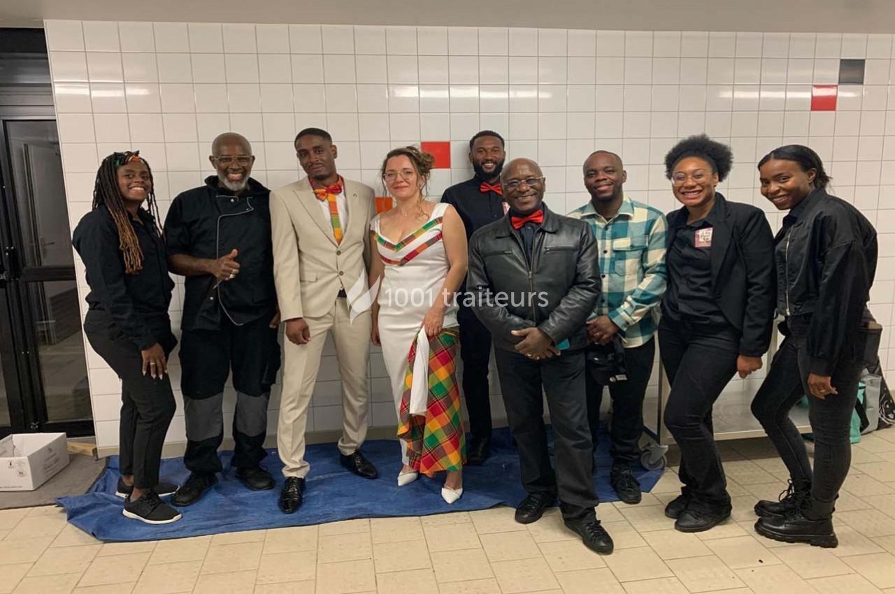 Un groupe de personnes posant ensemble dans un couloir carrelé, certaines en tenue élégante et colorée.