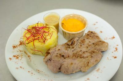 Assiette garnie de brochettes sur un ananas, accompagnée de légumes, sauces et bouchées frites.