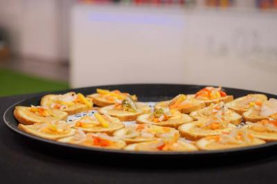 Assiette garnie de brochettes sur un ananas, accompagnée de légumes, sauces et bouchées frites.