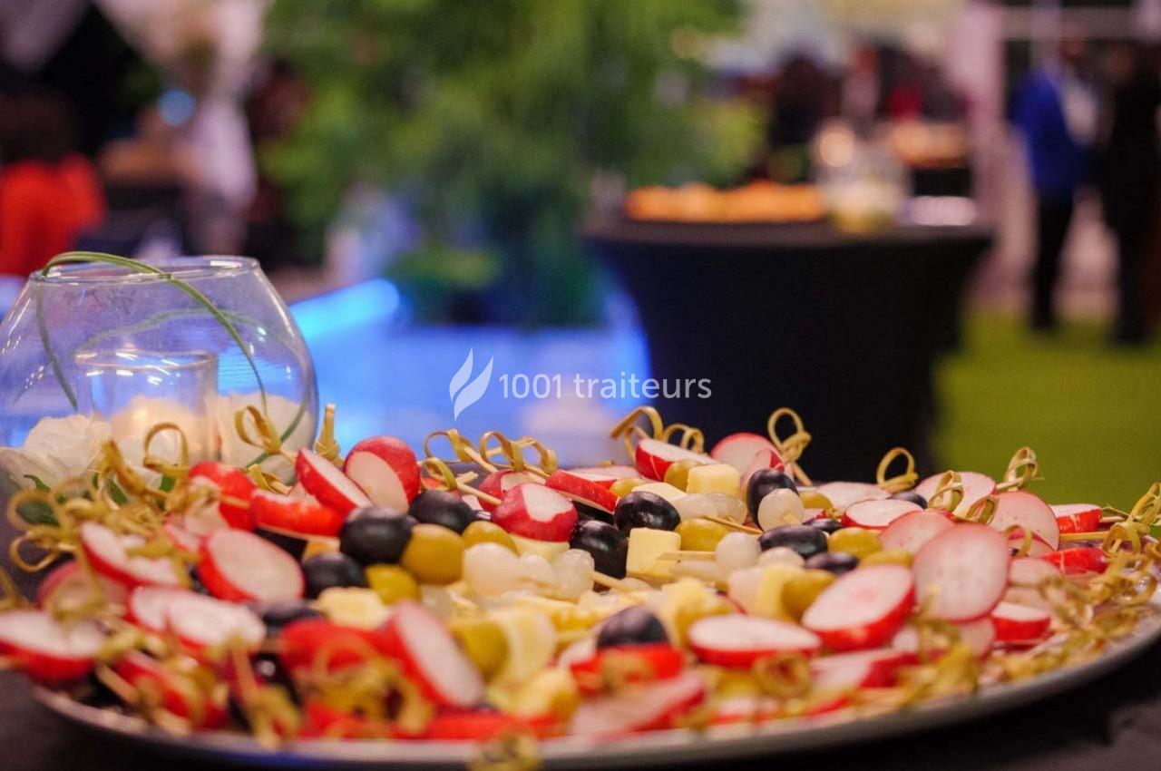 Plateau de brochettes apéritives avec radis, raisins, fromage et olives, présenté sur une table lors d'un événement.