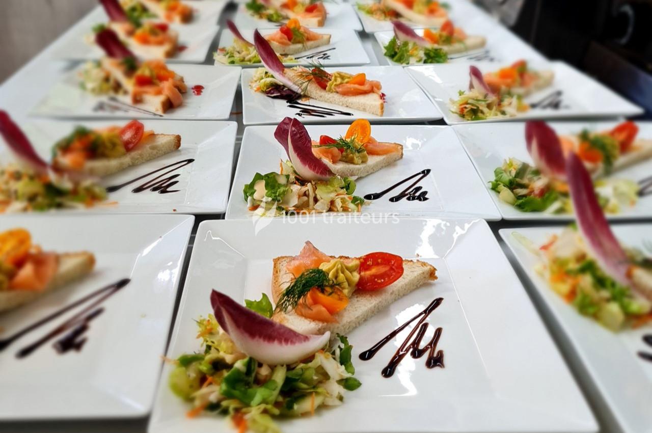 Assiettes dressées avec des toasts au saumon, crudités, endives rouges et filet de sauce balsamique.