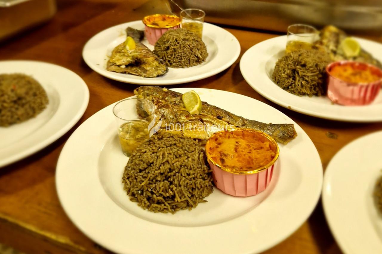 Assiettes servies avec du poisson grillé, du riz, une sauce en verrine et un accompagnement dans une coupelle rose.