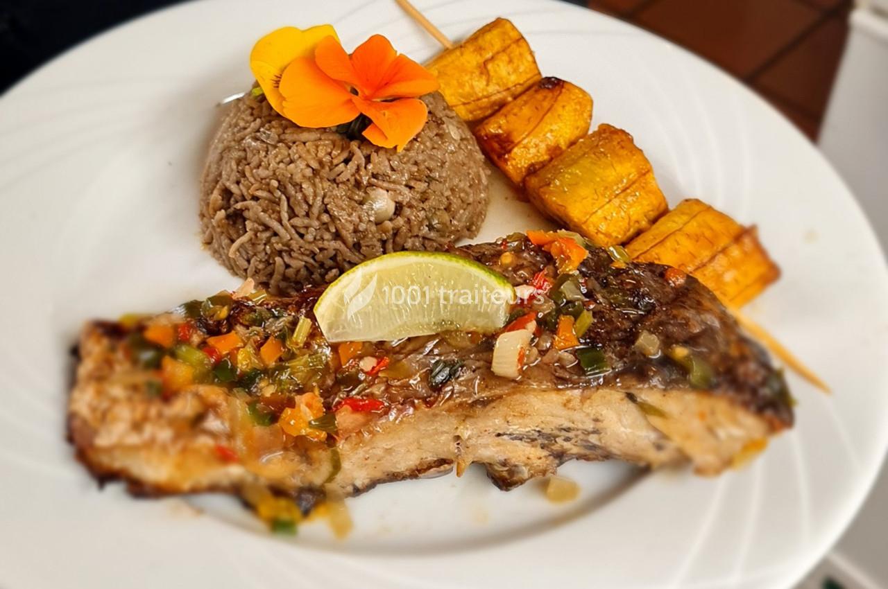 Assiette composée de poisson grillé avec sauce, riz aux haricots, brochettes de bananes plantains et une fleur décorative.
