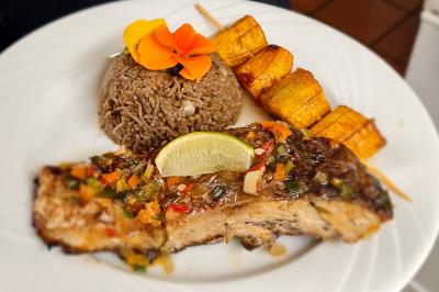 Assiette garnie de brochettes sur un ananas, accompagnée de légumes, sauces et bouchées frites.