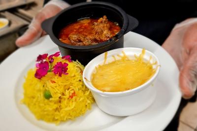 Assiette garnie de brochettes sur un ananas, accompagnée de légumes, sauces et bouchées frites.