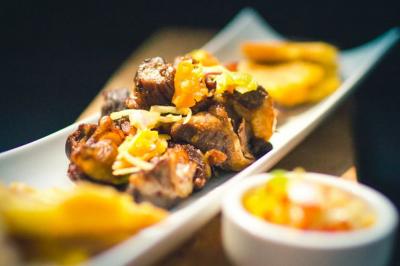 Assiette garnie de brochettes sur un ananas, accompagnée de légumes, sauces et bouchées frites.