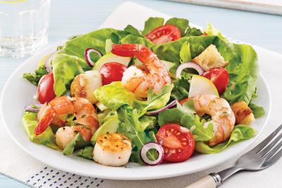 Assiette garnie de brochettes sur un ananas, accompagnée de légumes, sauces et bouchées frites.
