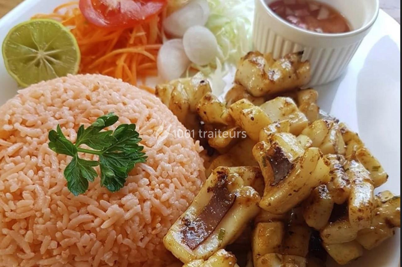 Assiette composée de riz orange, légumes frais, morceaux de calamars grillés et une sauce servie dans un ramequin.