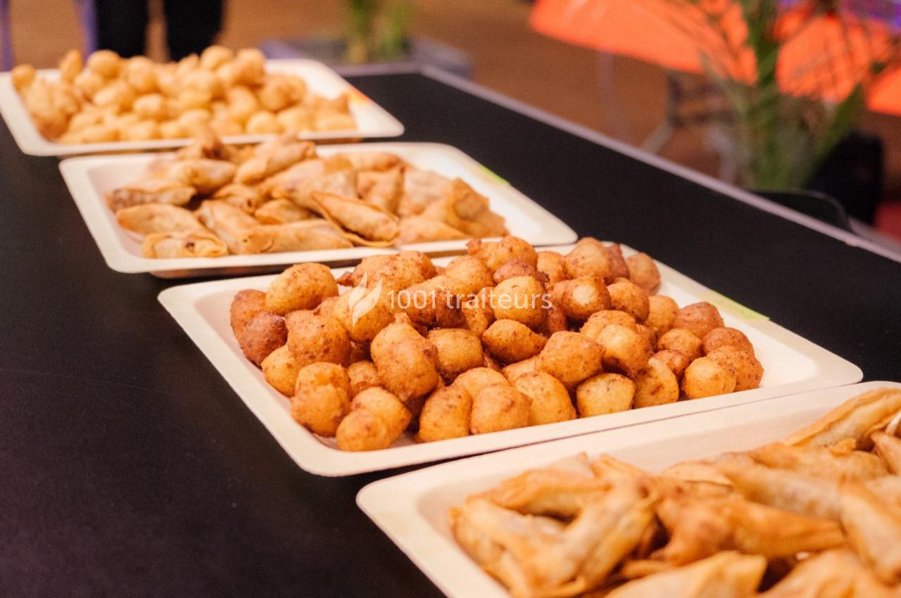 Assortiment de snacks frits disposés sur des plateaux en carton sur une table noire.