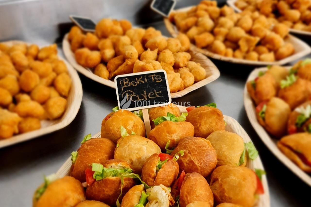 Assortiment de beignets dorés et bouchées apéritives présentés sur des plateaux en bois.