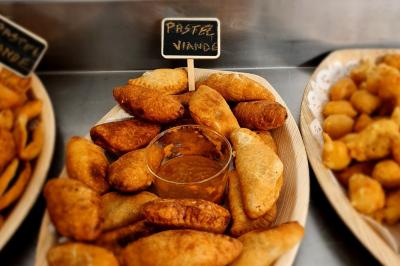 Assiette garnie de brochettes sur un ananas, accompagnée de légumes, sauces et bouchées frites.