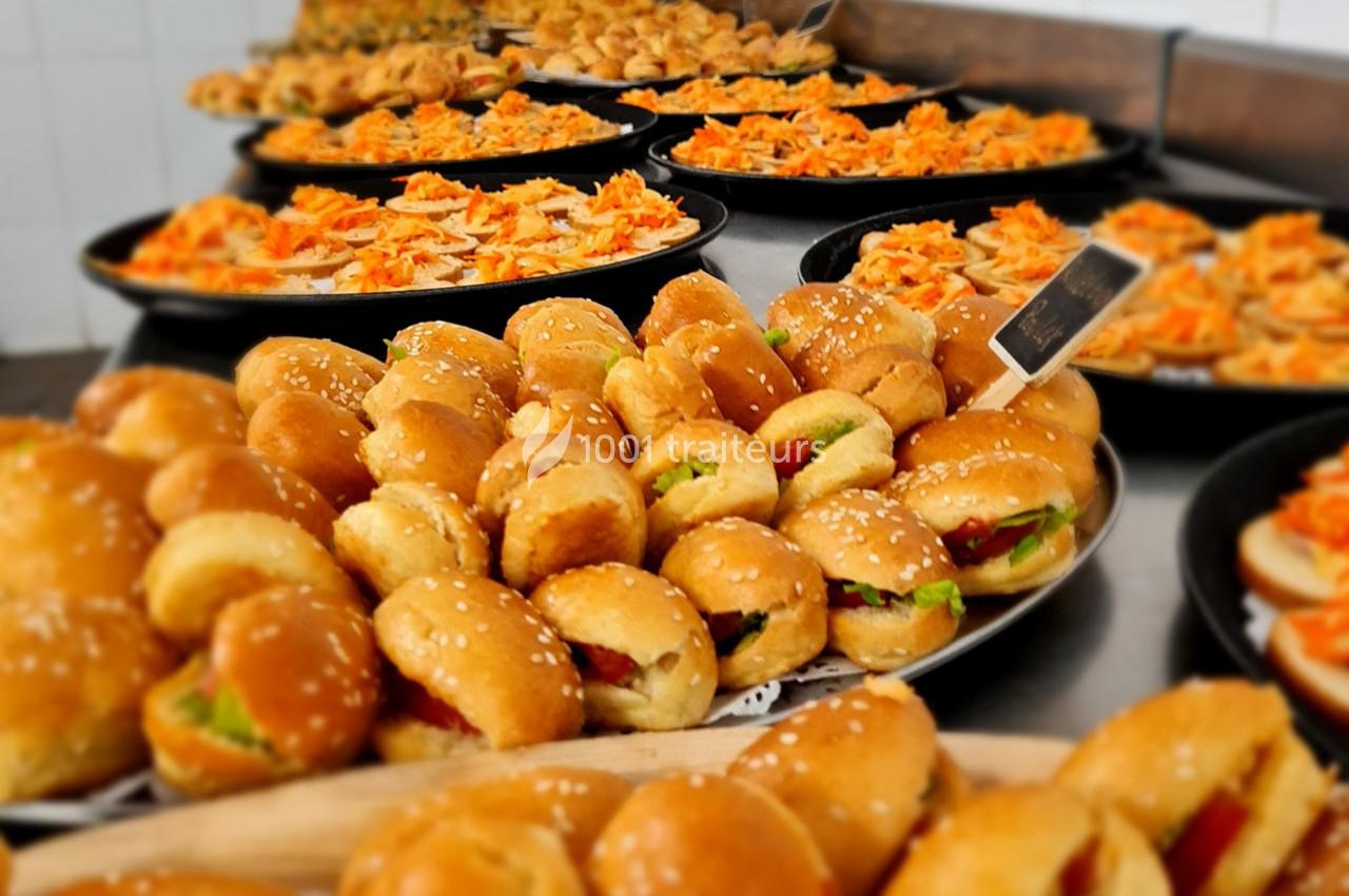 Plateaux garnis de mini-sandwichs, pizzas et amuse-bouches variés disposés sur une table dans un cadre traiteur.