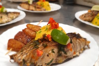 Assiette garnie de brochettes sur un ananas, accompagnée de légumes, sauces et bouchées frites.