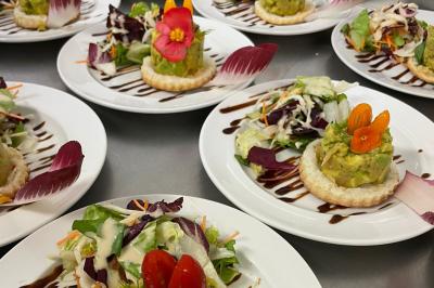 Assiette garnie de brochettes sur un ananas, accompagnée de légumes, sauces et bouchées frites.