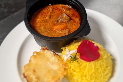 Assiette garnie de brochettes sur un ananas, accompagnée de légumes, sauces et bouchées frites.