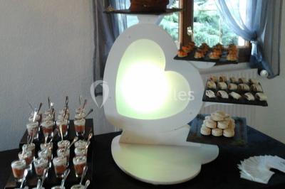 Table de buffet dressée en extérieur avec boissons, verrines, desserts et une pièce montée sur une nappe noire.