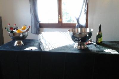 Table de buffet dressée en extérieur avec boissons, verrines, desserts et une pièce montée sur une nappe noire.