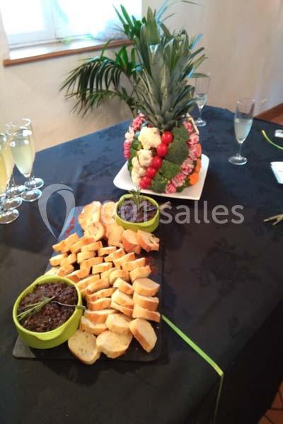 Plateau de toasts avec tapenade et centre de table décoratif en fruits et légumes sur une nappe noire.