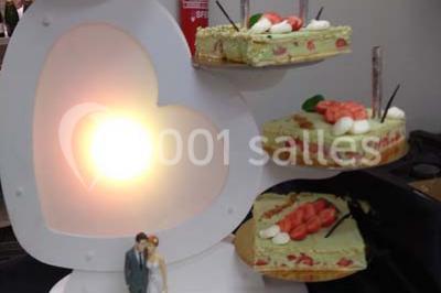 Table de buffet dressée en extérieur avec boissons, verrines, desserts et une pièce montée sur une nappe noire.