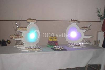 Table de buffet dressée en extérieur avec boissons, verrines, desserts et une pièce montée sur une nappe noire.