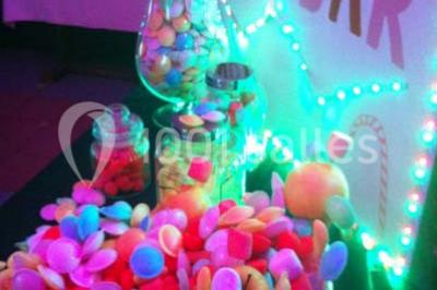 Table de buffet dressée en extérieur avec boissons, verrines, desserts et une pièce montée sur une nappe noire.