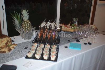 Table de buffet dressée en extérieur avec boissons, verrines, desserts et une pièce montée sur une nappe noire.