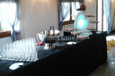 Table de buffet dressée en extérieur avec boissons, verrines, desserts et une pièce montée sur une nappe noire.