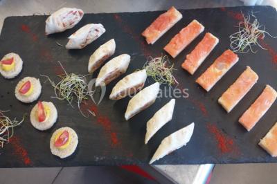 Table de buffet dressée en extérieur avec boissons, verrines, desserts et une pièce montée sur une nappe noire.